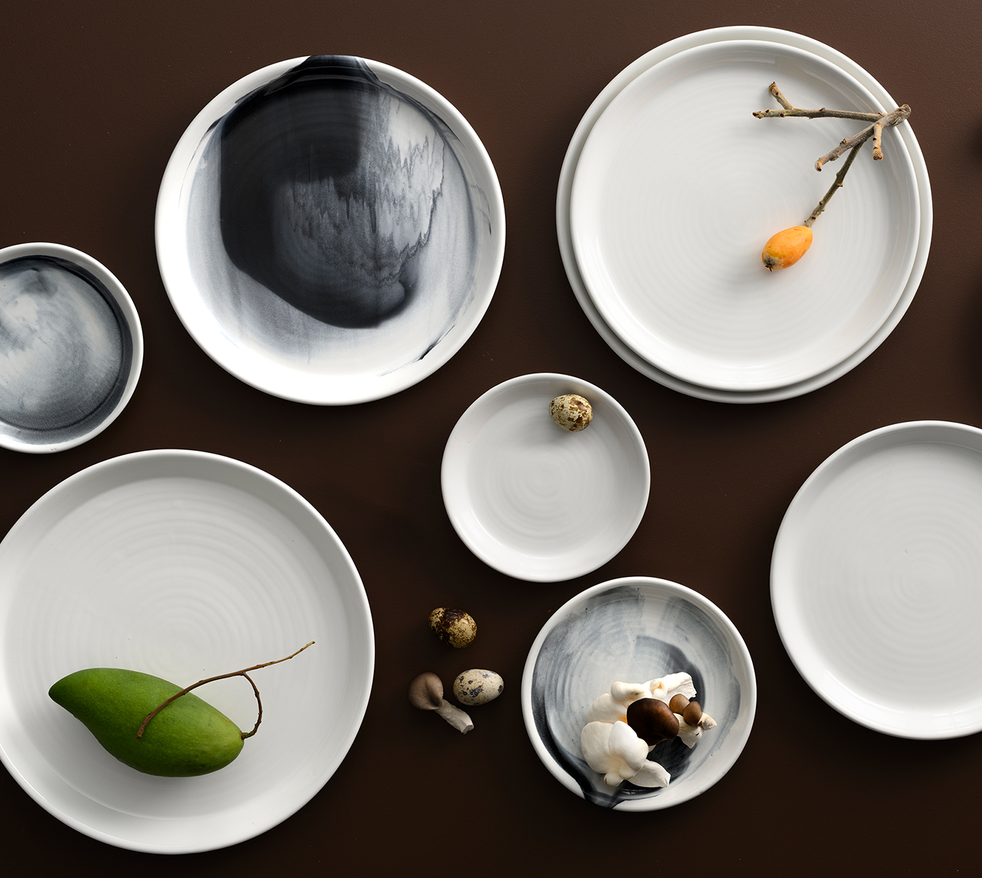 Flat lay of POTTR Finn Black Smoke crockery collection, featuring handcrafted pottery plates and bowls with white and smoky black glaze finishes, now available at Chef&rsquo;s Hat.