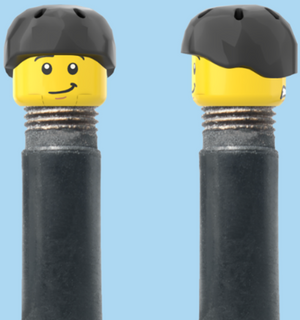 `A NEW ITEM  -  Brick Caps - Schrader Valve - 2 Face Head (Worried Look & Half Smile) with a Black Helmet
