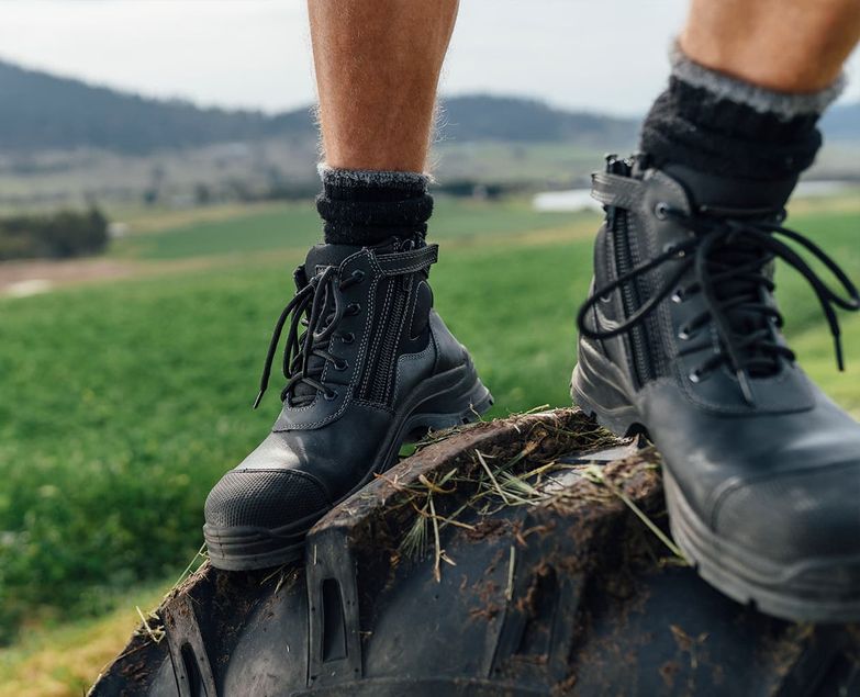 Worker standing on a tractor tire in lace up safety boots