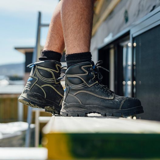 Worker putting on safety boot sitting on stool