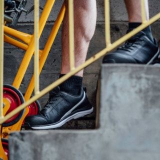 A pair of safety shoes worn by a man as he walks downstairs.