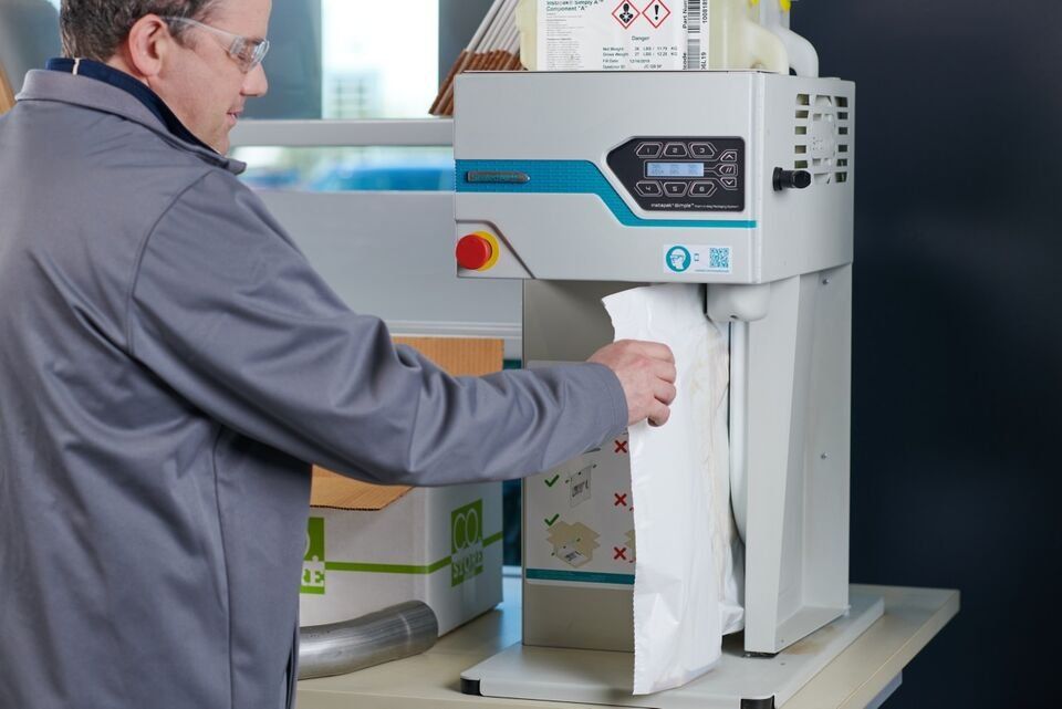 Operator filling a foam bag on the Instapak Simple machine at a packing bench