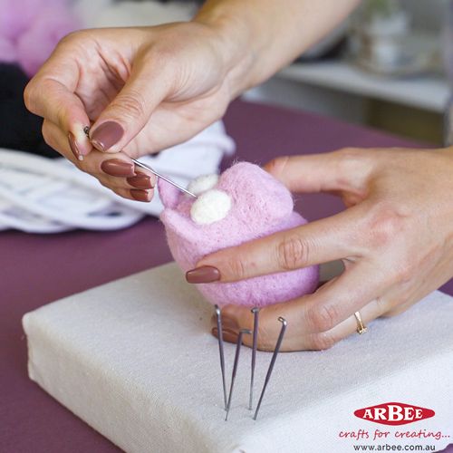 A woman making a toy pig using needle felting